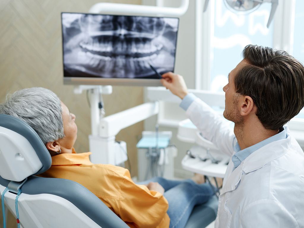 An elderly patient with her dentist going over her x-rays and dental results.
