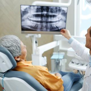 An elderly patient with her dentist going over her x-rays and dental results.