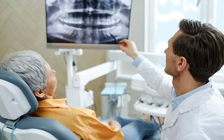 Image of a patient in a dental chair being shown x-rays of their treatment with her dentist.