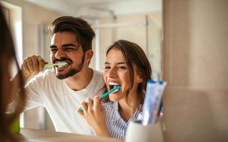 Young couple brushing their teeth in mirror