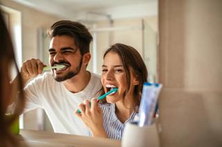 Image of a couple brushing their teeth, practicing preventative dentistry.