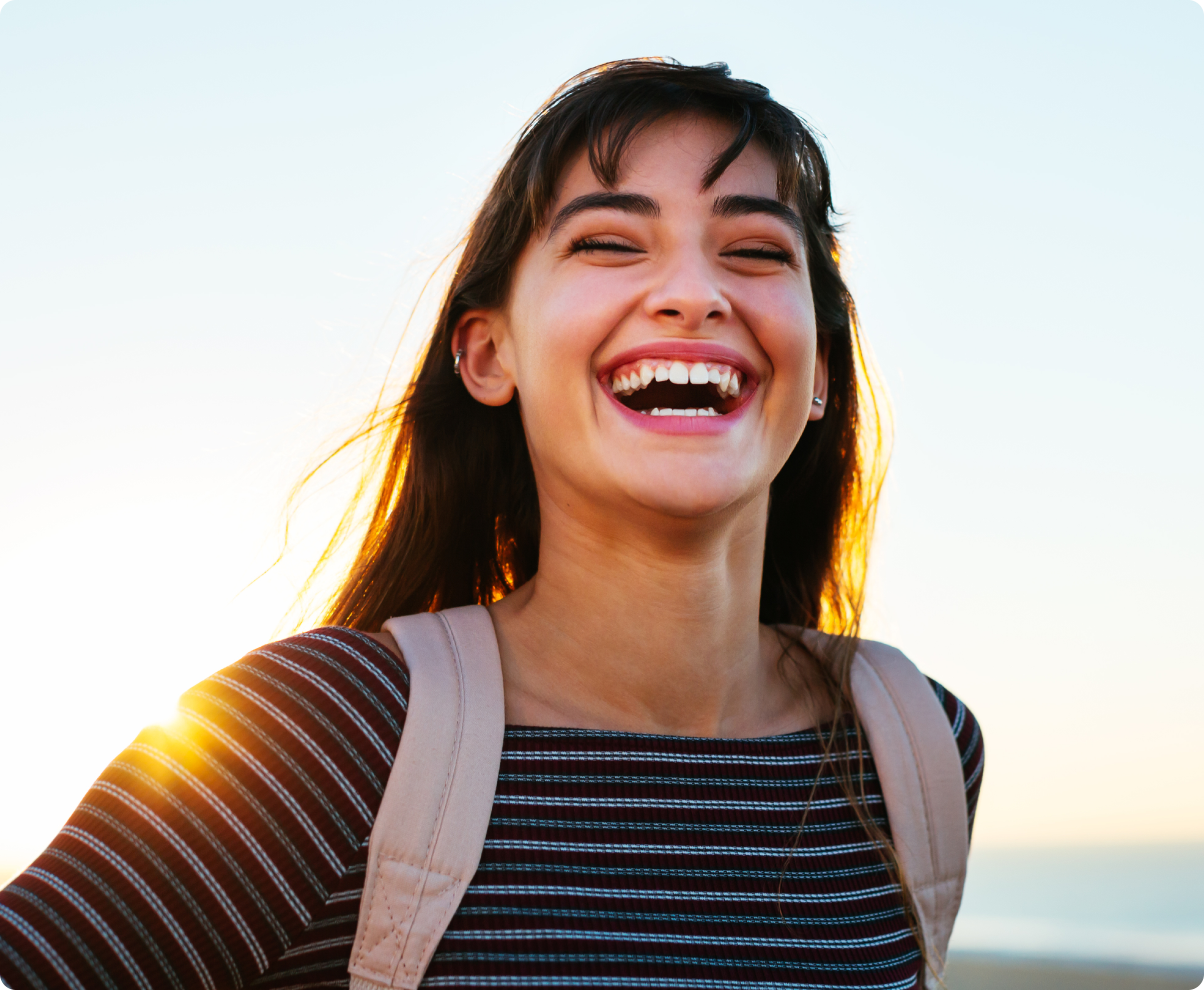 Image of a women with white healthy teeth, she is over joyed being outside.