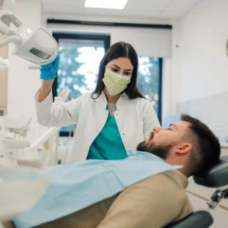 Male patient sits on a dental chair to check his teeth for his Invisalign consultation.
