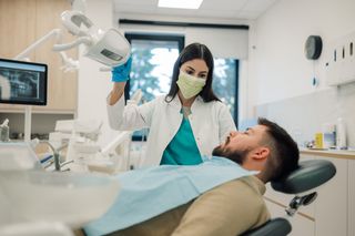 Image of a dentist caring for her patient in a dental chair at her clinic.