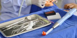 Image of a dentist with a patient with dental tool in the foreground.