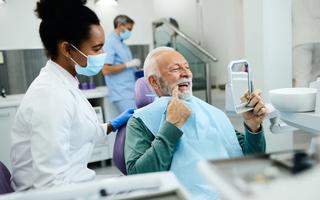 Senior patient inspecting recent dental treatment