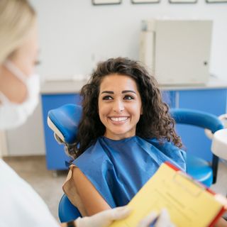A young female in a dental chair with her dentist going over her oral examination.