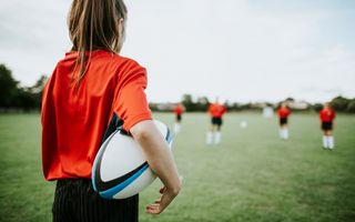 Image of a young female in the field with a rugby ball.