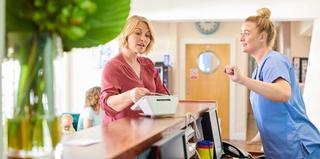 Image of patient at the reception desk with a staff member the dental practice.