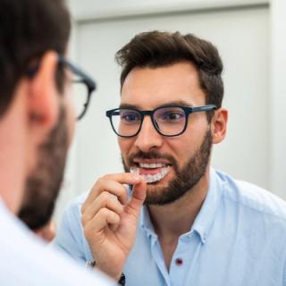 Image of patient at their home putting on his clear aligners in front of the mirror.