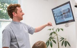 Image of a dentist showing his young patient her x-rays results.