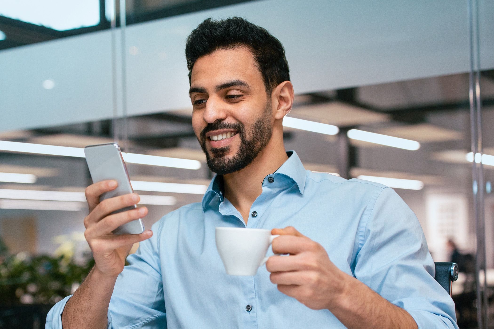 Image of a man drinking his coffee, taking his time looking at his phone.