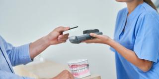 Stock image of a person submitting a payment to a dentist receptionist.