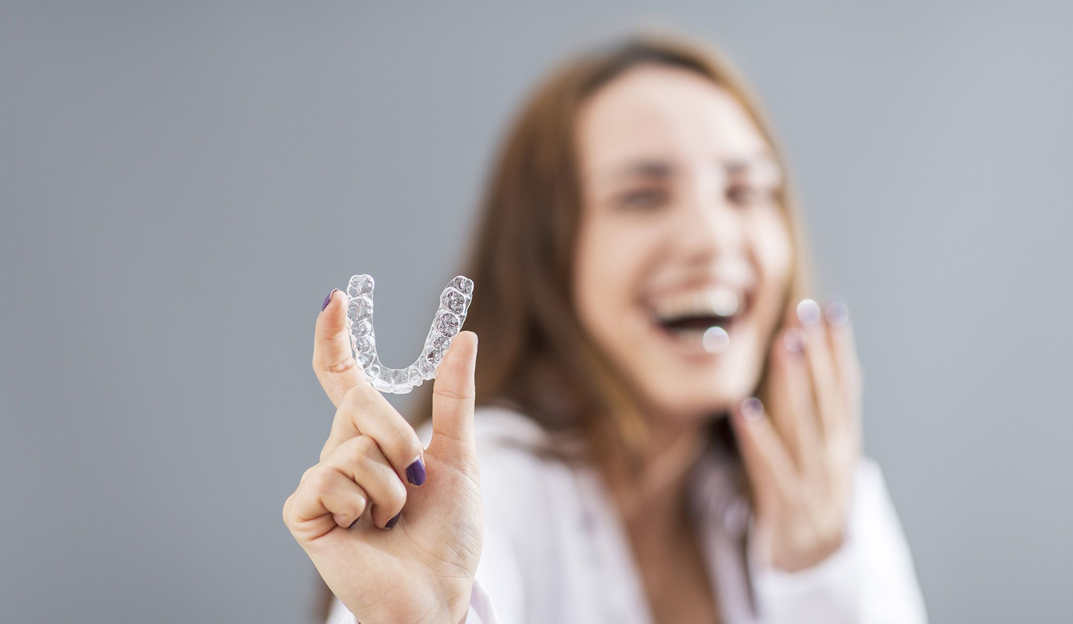 Image of a young lady showing her Invisalign aligners.
