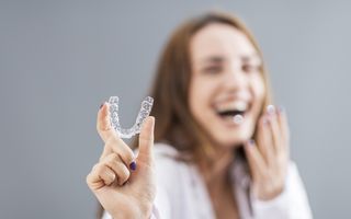 Image of a young lady showing her Invisalign aligners.