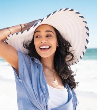 Stock image of female at the beach with a hat and a big smile