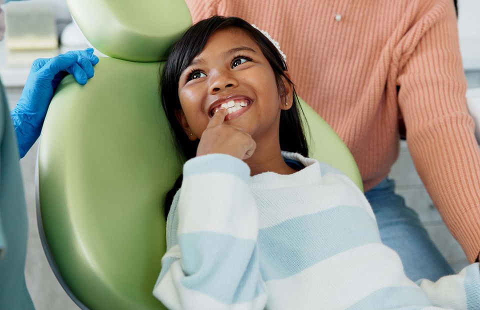 Child sitting in a dental chair with a parent nearby