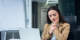 Image of a woman at work holding her mouth due to pain.