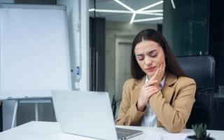 Image of a women in a corporate setting holding her jaw in pain.