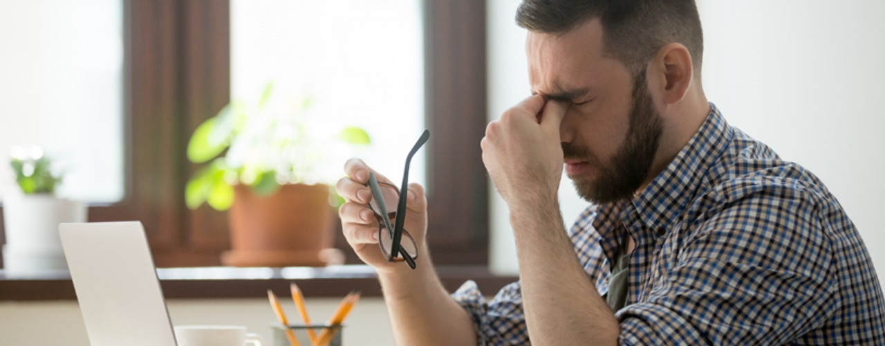 Man with headache at computer quitting smoking