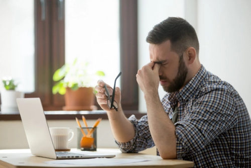 Man with headache at computer quitting smoking