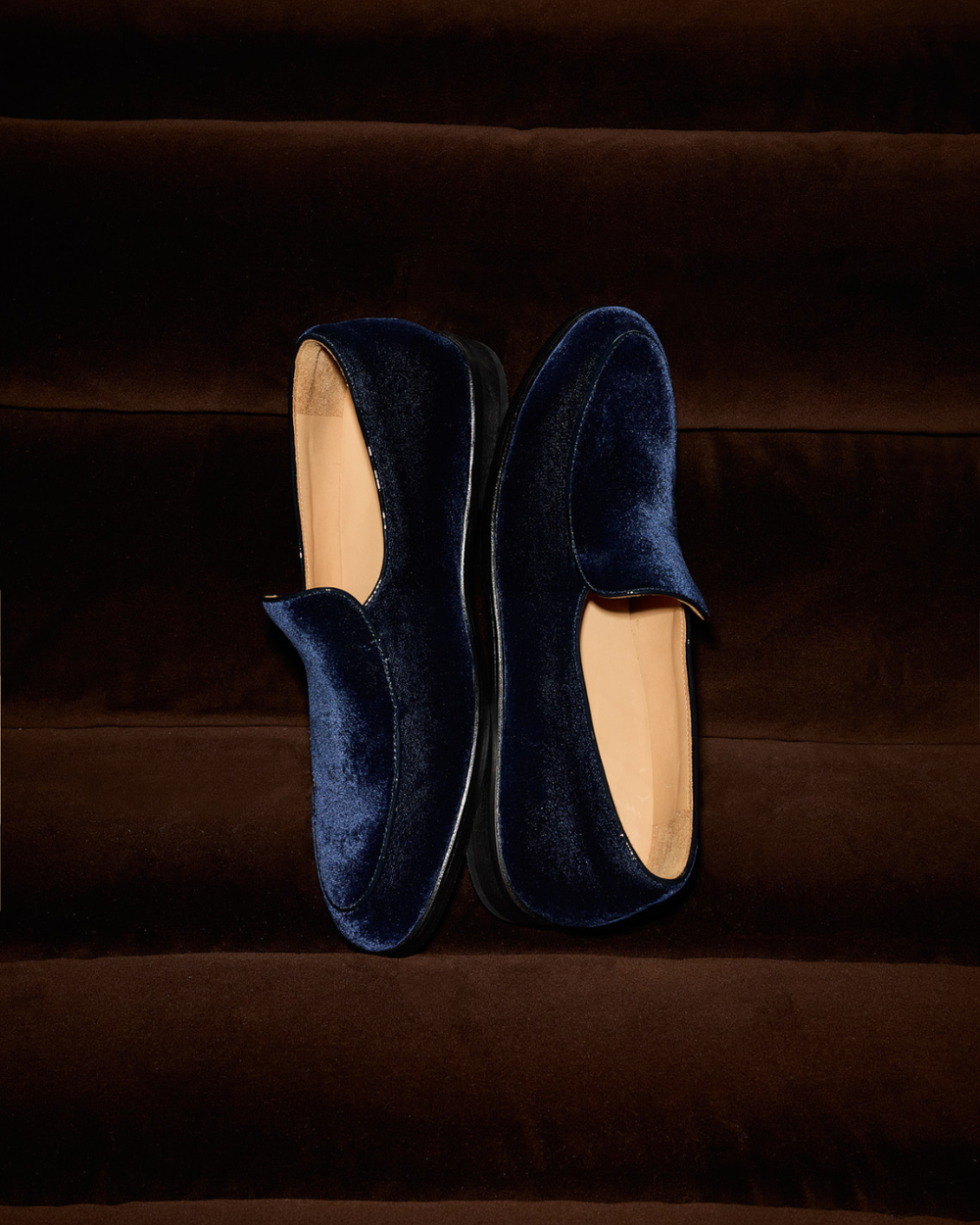 Pair of navy velvet loafers on a couch