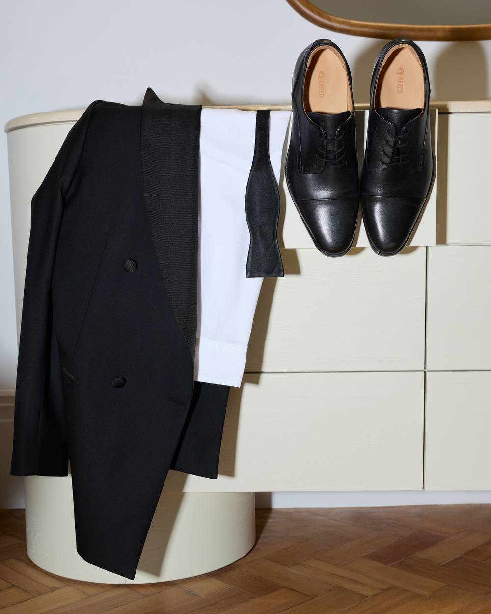 A suit and dress shoes hanging on a chest of drawers