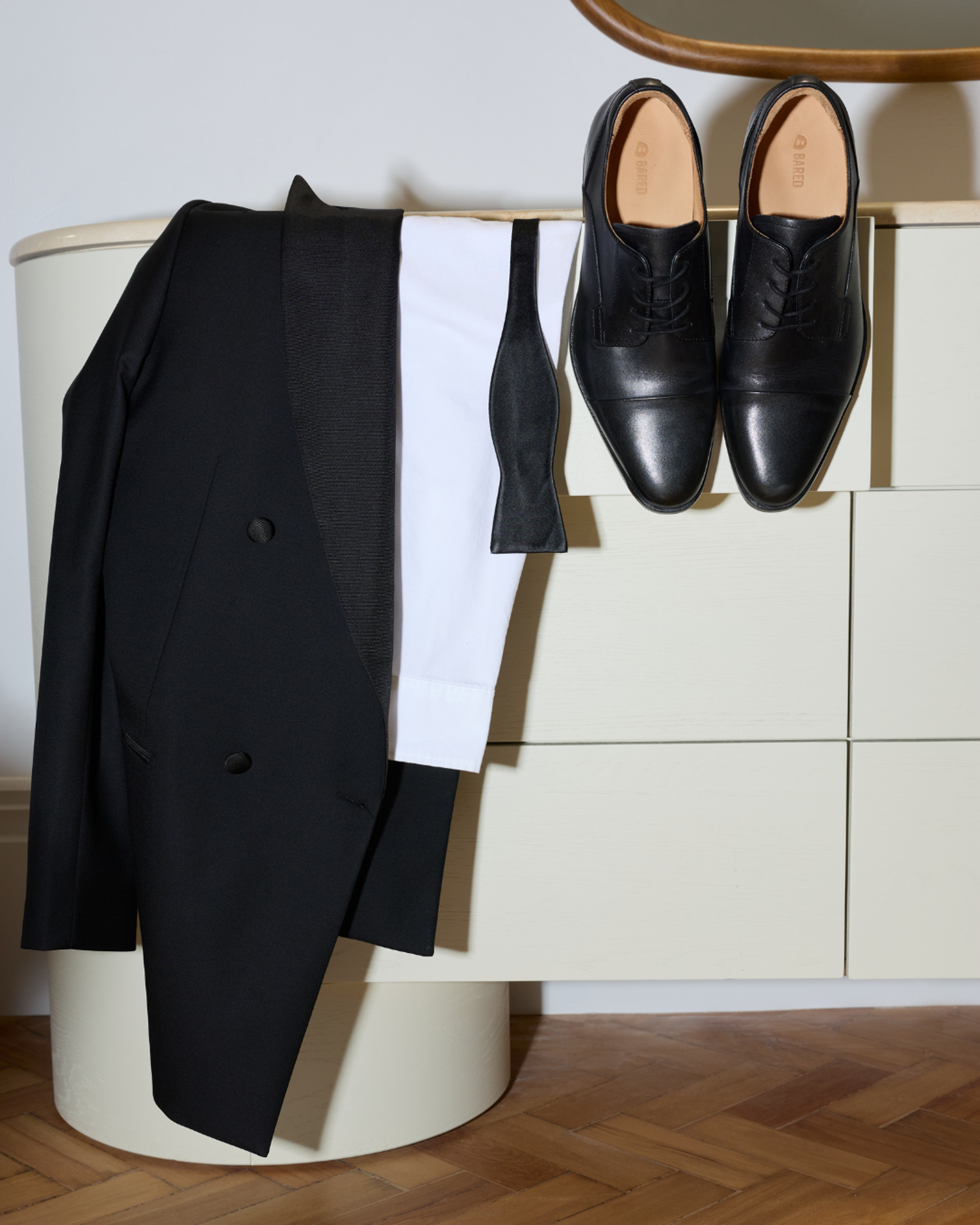 A suit and dress shoes hanging on a chest of drawers
