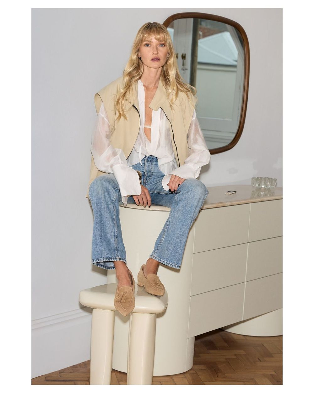 woman sitting on a bench wearing jeans and pointed suede loafers