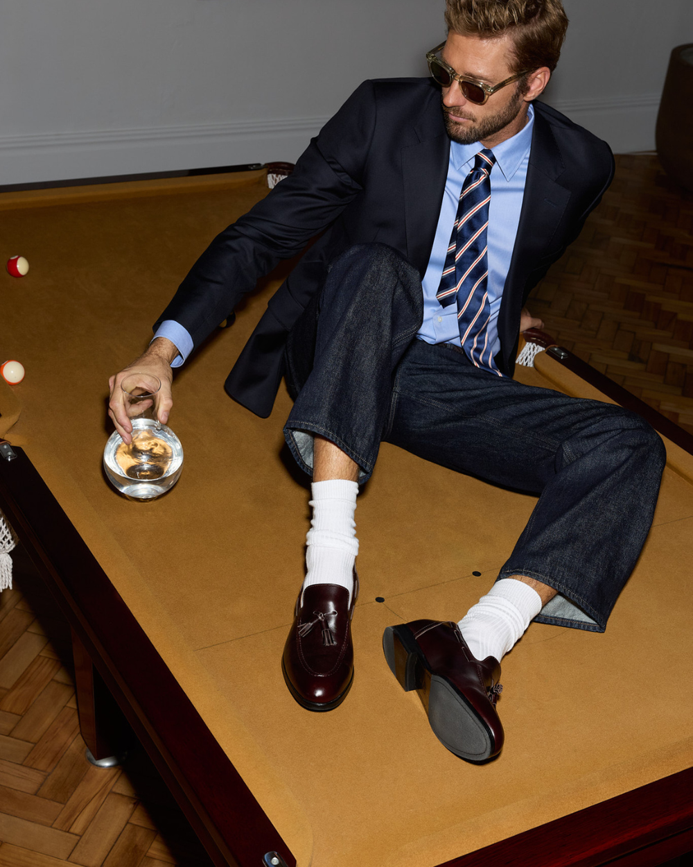 Man sitting on a pool table wearing a suit and brown tassel loafers