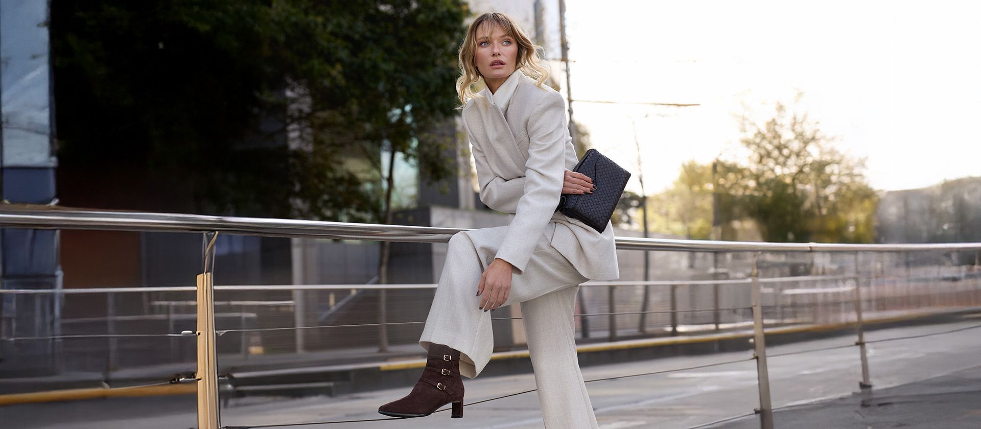 Woman wearing brown heeled boots and a white suit