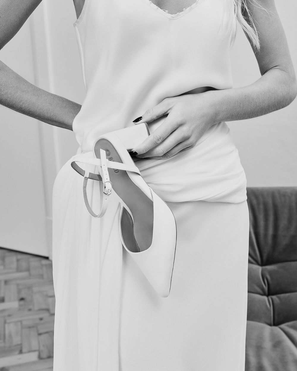 Model holding a white pointed toe bridal heel in black and white