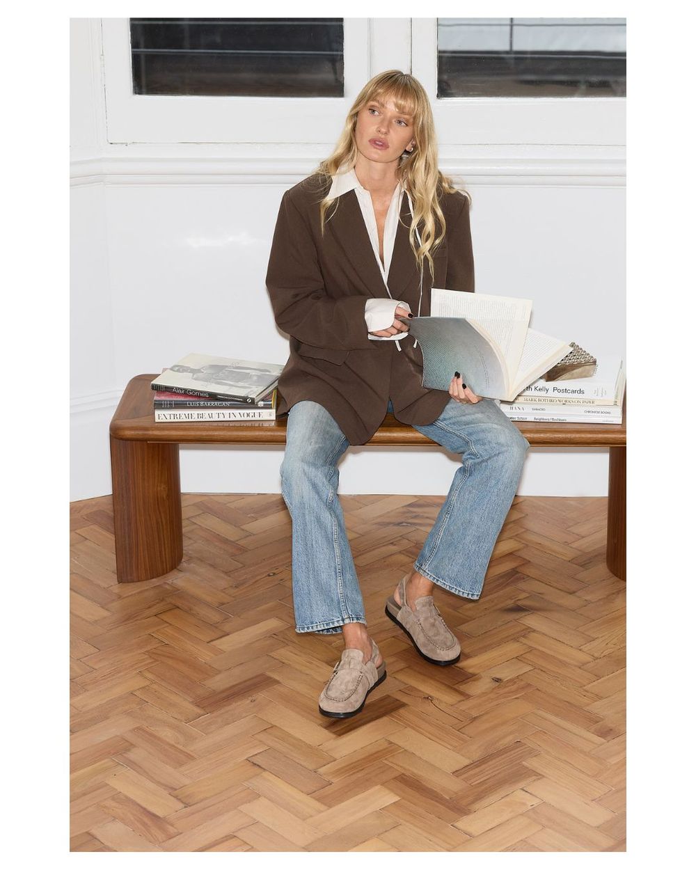 Woman sitting on a bench wearing suede clogs 