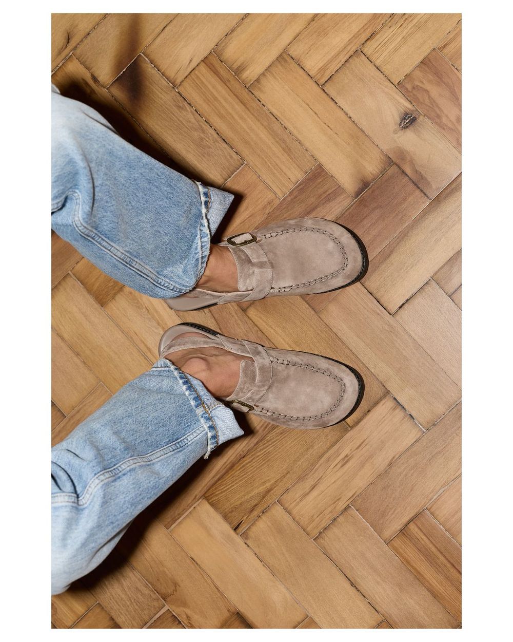 Pair of suede clogs on a wooden floor
