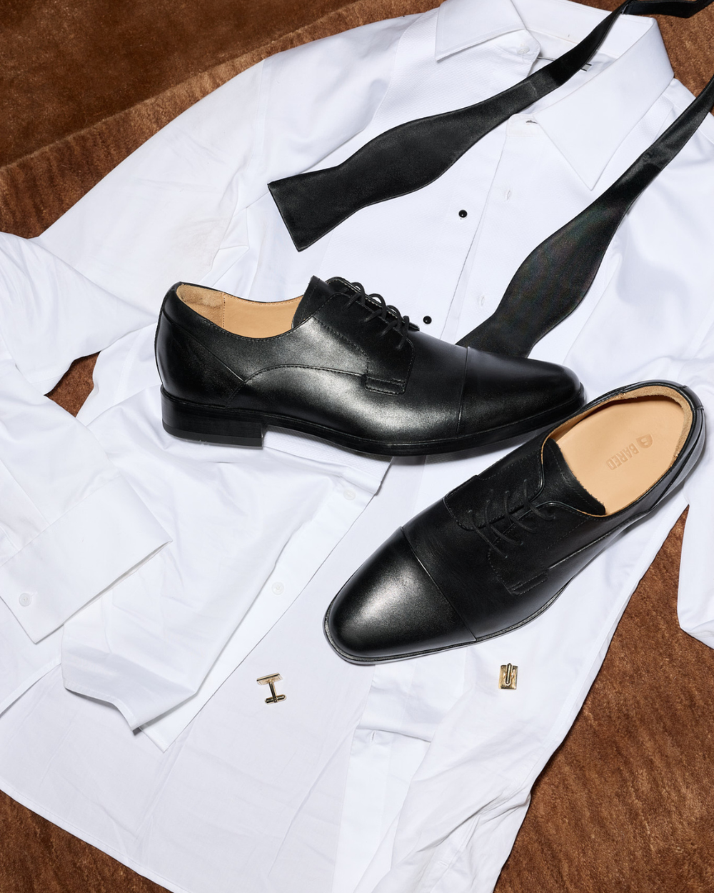 Flatlay of a shirt, cufflinks and black leather dress shoes