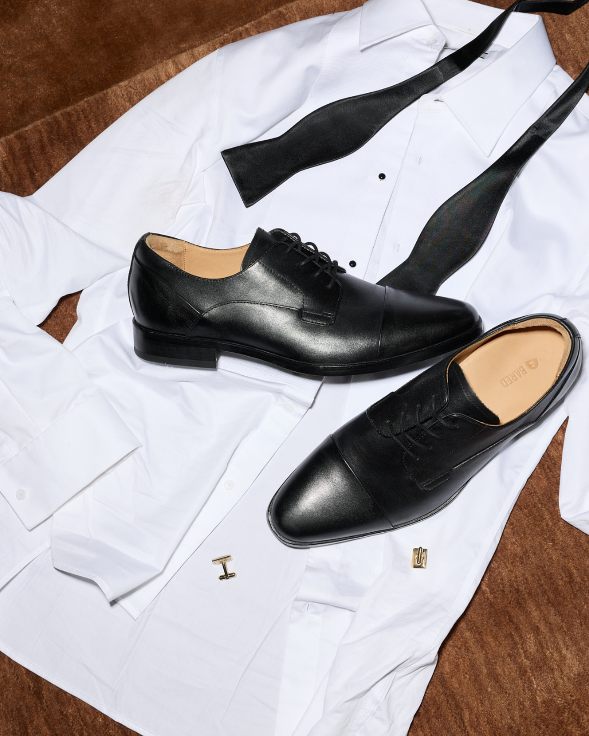Flatlay of a shirt, cufflinks and black leather dress shoes