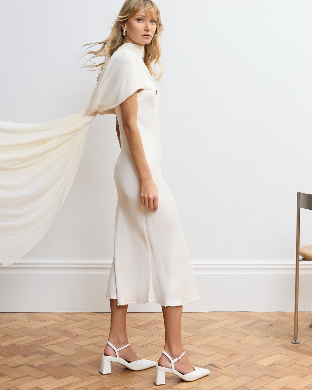 model standing with a white dress and white block heels with pointed toes