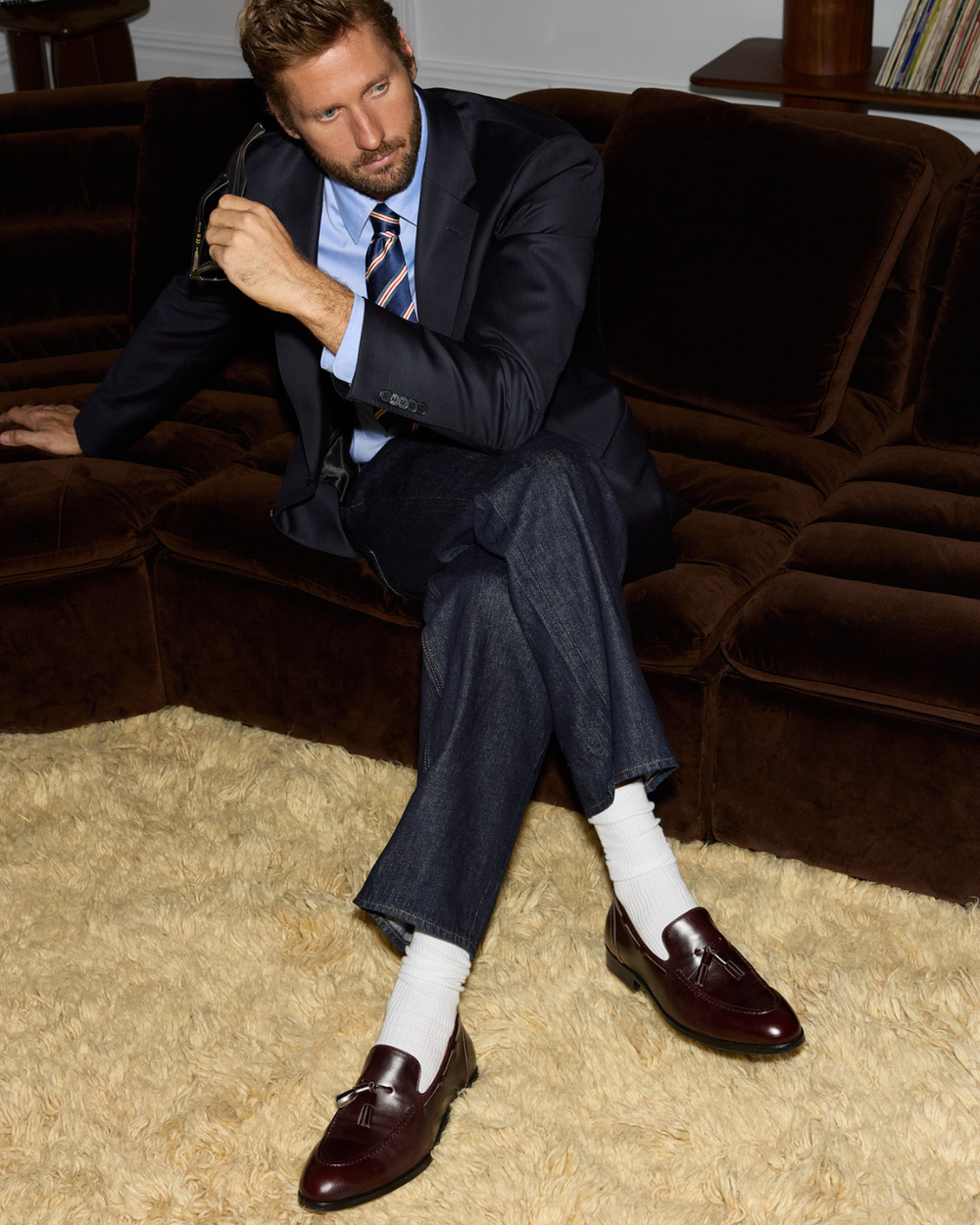 Man sitting on a coach wearing a suit and loafers with tassels