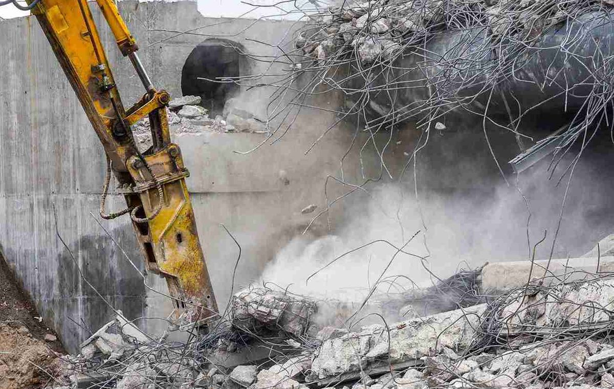 Hydraulic excavator breaking reinforced concrete and loading demolition debris for professional concrete breaking and hauling services in Sydney, NSW.