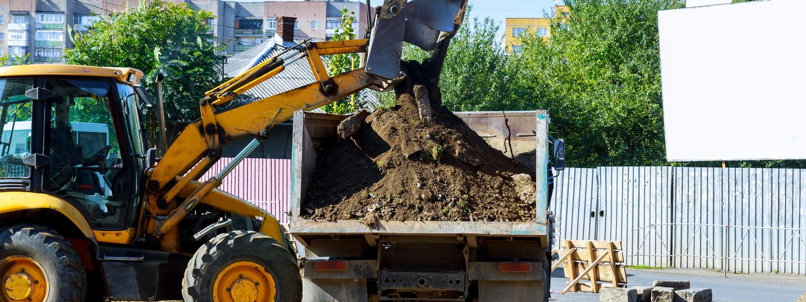 Excavator loading excavated soil into a truck and dog trailer during professional dirt removal services in Sydney, NSW.