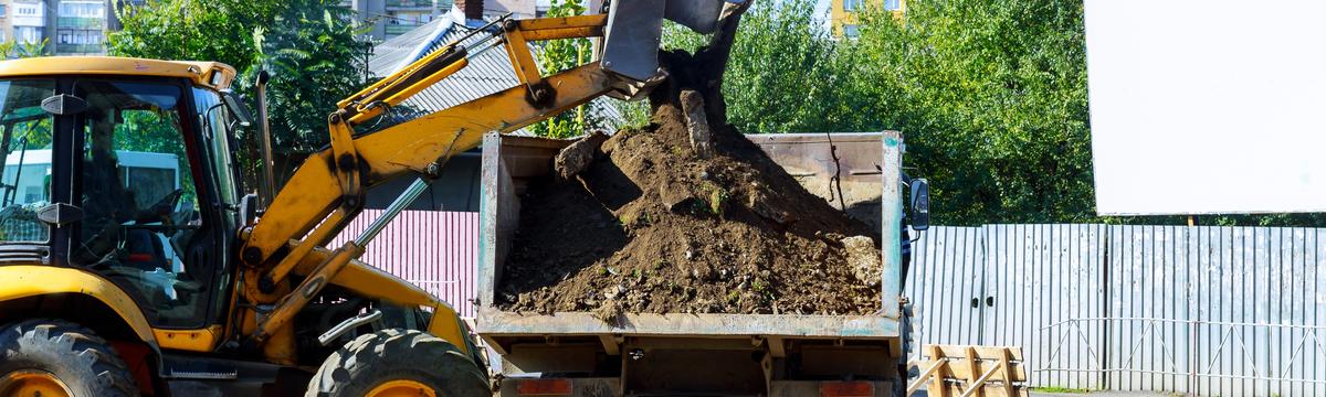 Excavator loading excavated soil into a truck and dog trailer during professional dirt removal services in Sydney, NSW.