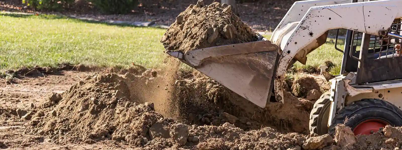 Skid steer loader scooping excavated soil for removal on a residential property in Sydney