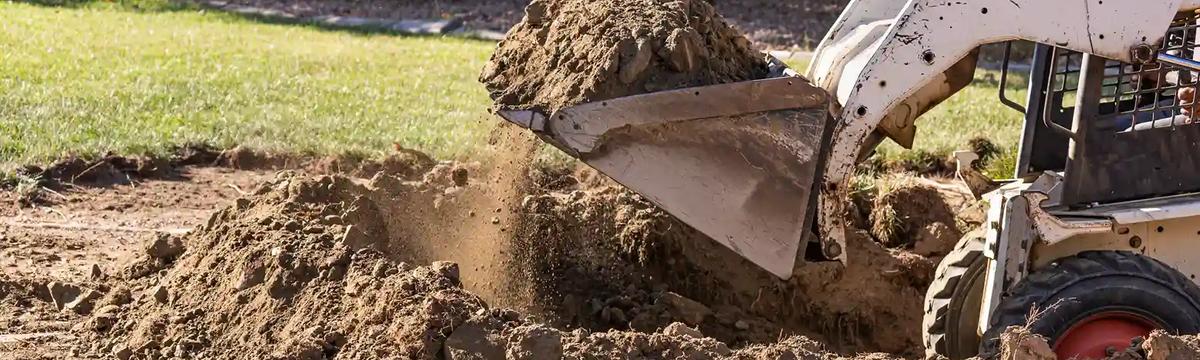 Skid steer loader scooping excavated soil for removal on a residential property in Sydney