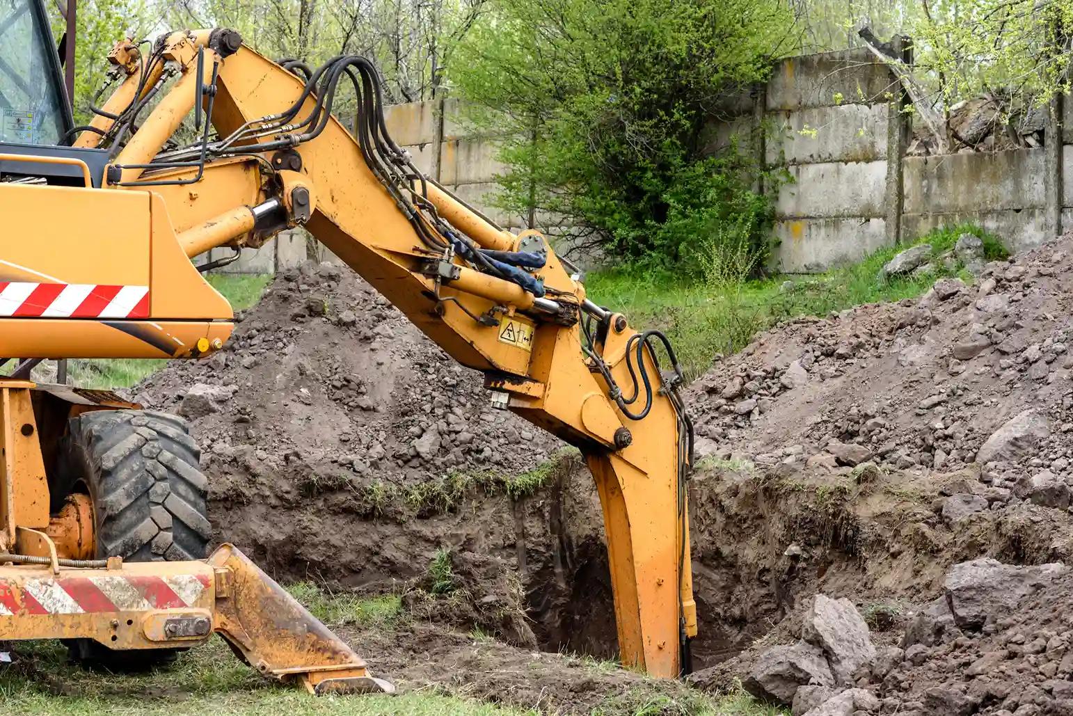 Excavator digging a trench with piles of excavated soil and spoil ready for removal in Sydney