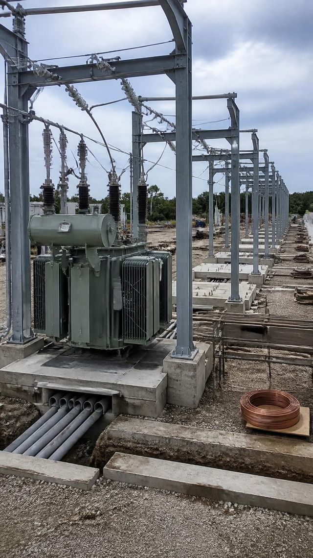 A power transformer on a concrete plinth with an open cable trench, empty transformer bays receding behind.