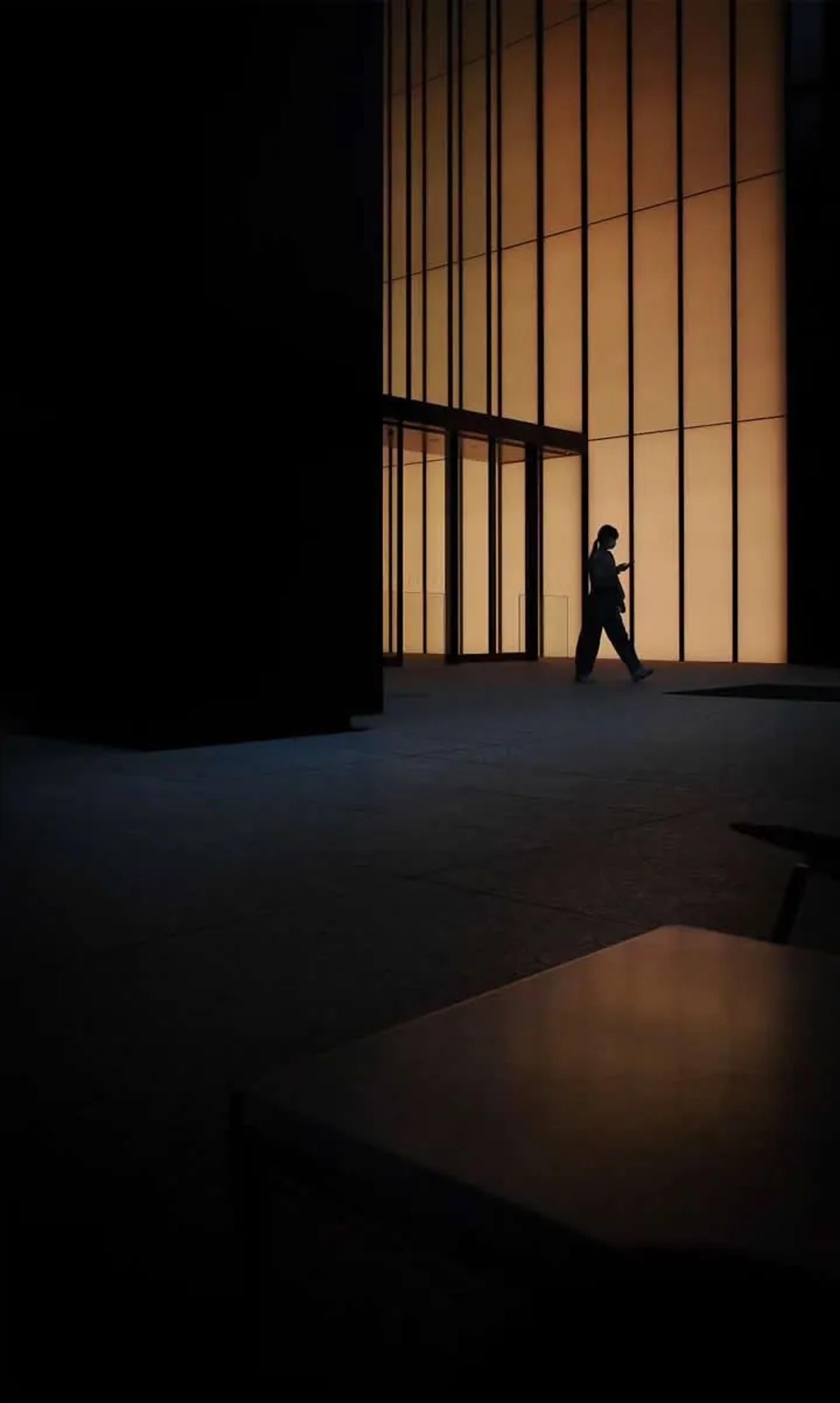 A person walking past lit office windows at night
