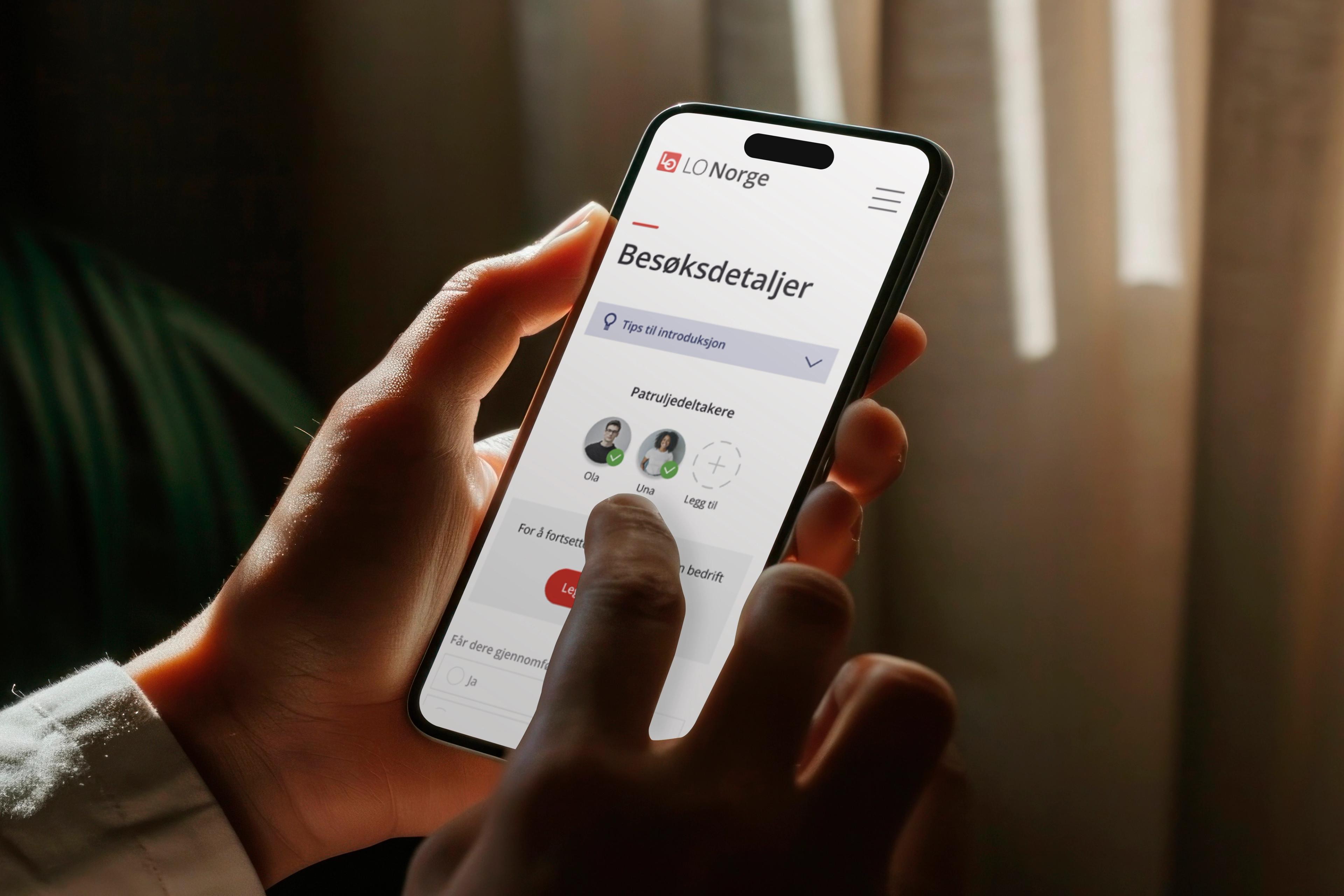Hånd holder smarttelefon. På skjerm oversikt over besøksdetaljer for en sommerpatrulje med bilde og navn av deltagere.