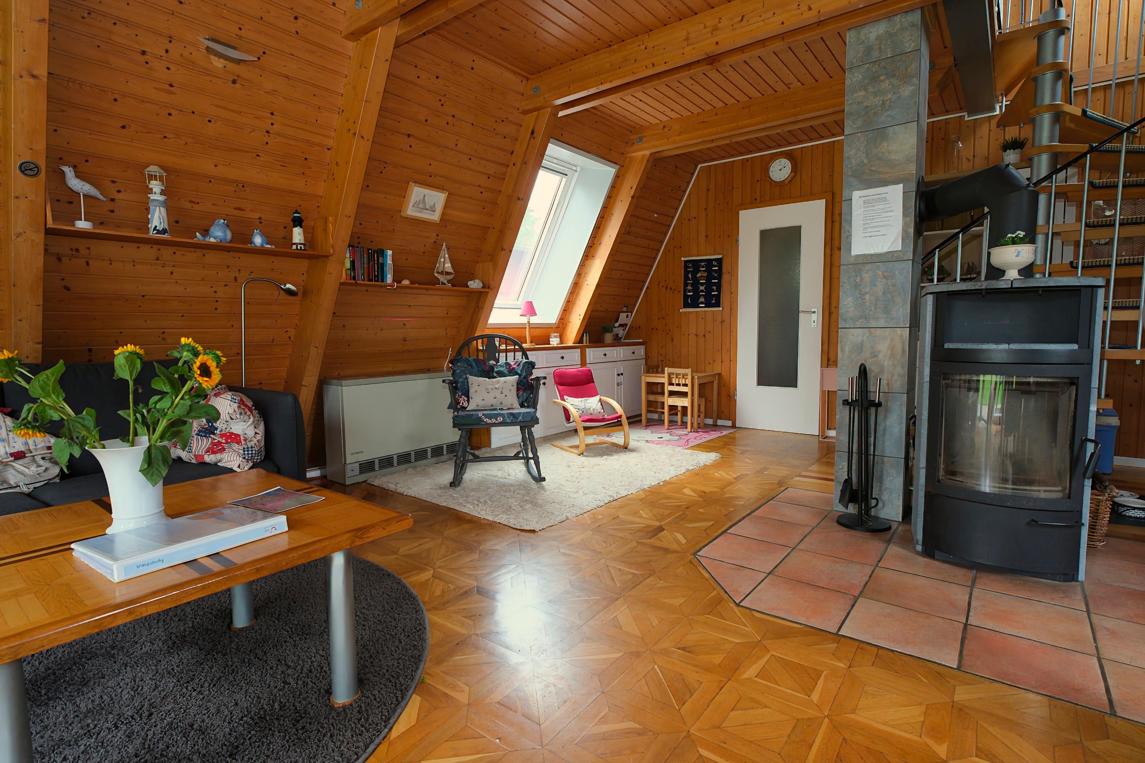 Ein gemütliches Wohnzimmer mit Holzverkleidung, Kamin und Dachfenster