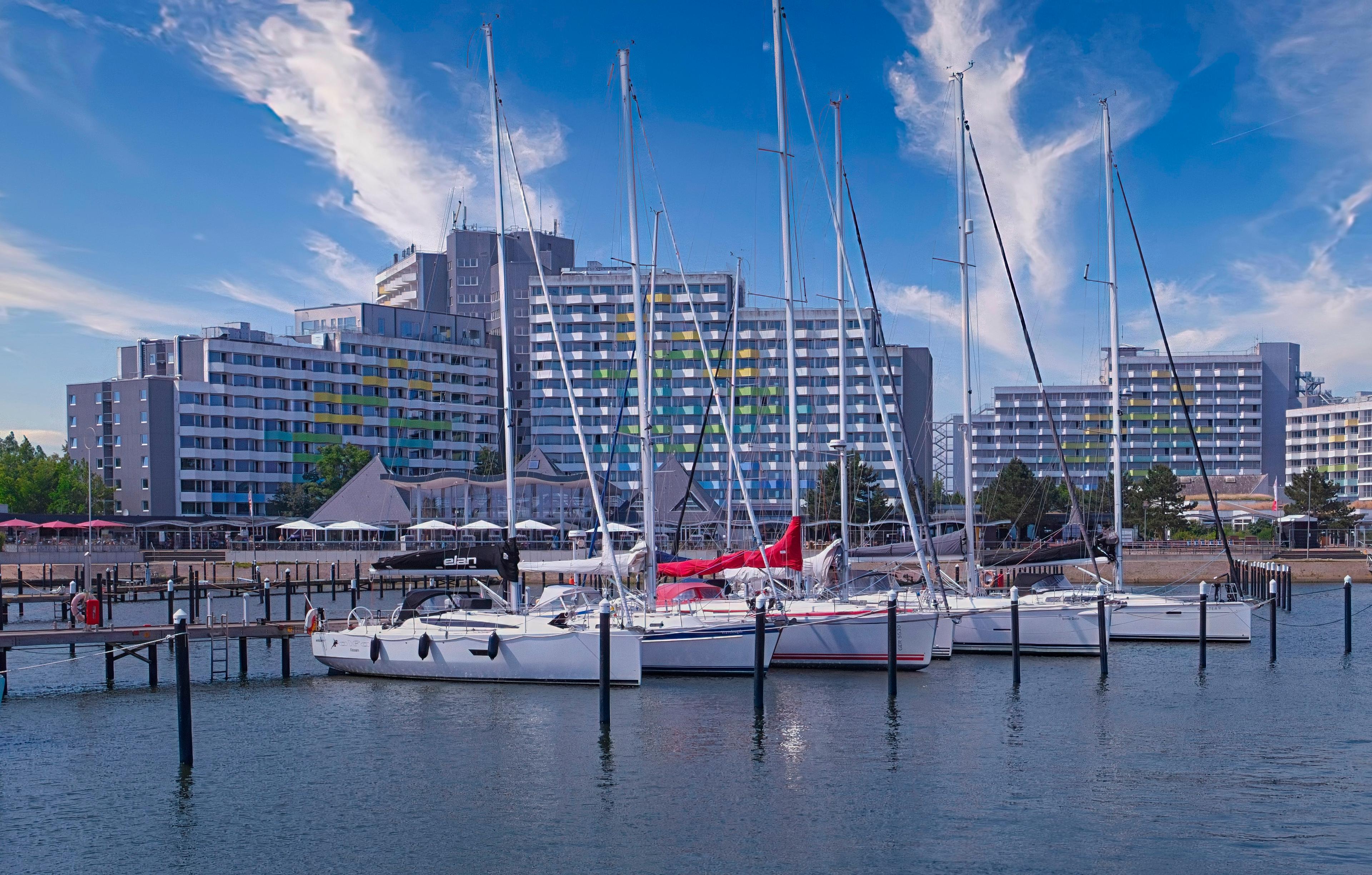 Ein moderner Yachthafen mit mehreren Segelbooten und Hochhäusern im Hintergrund