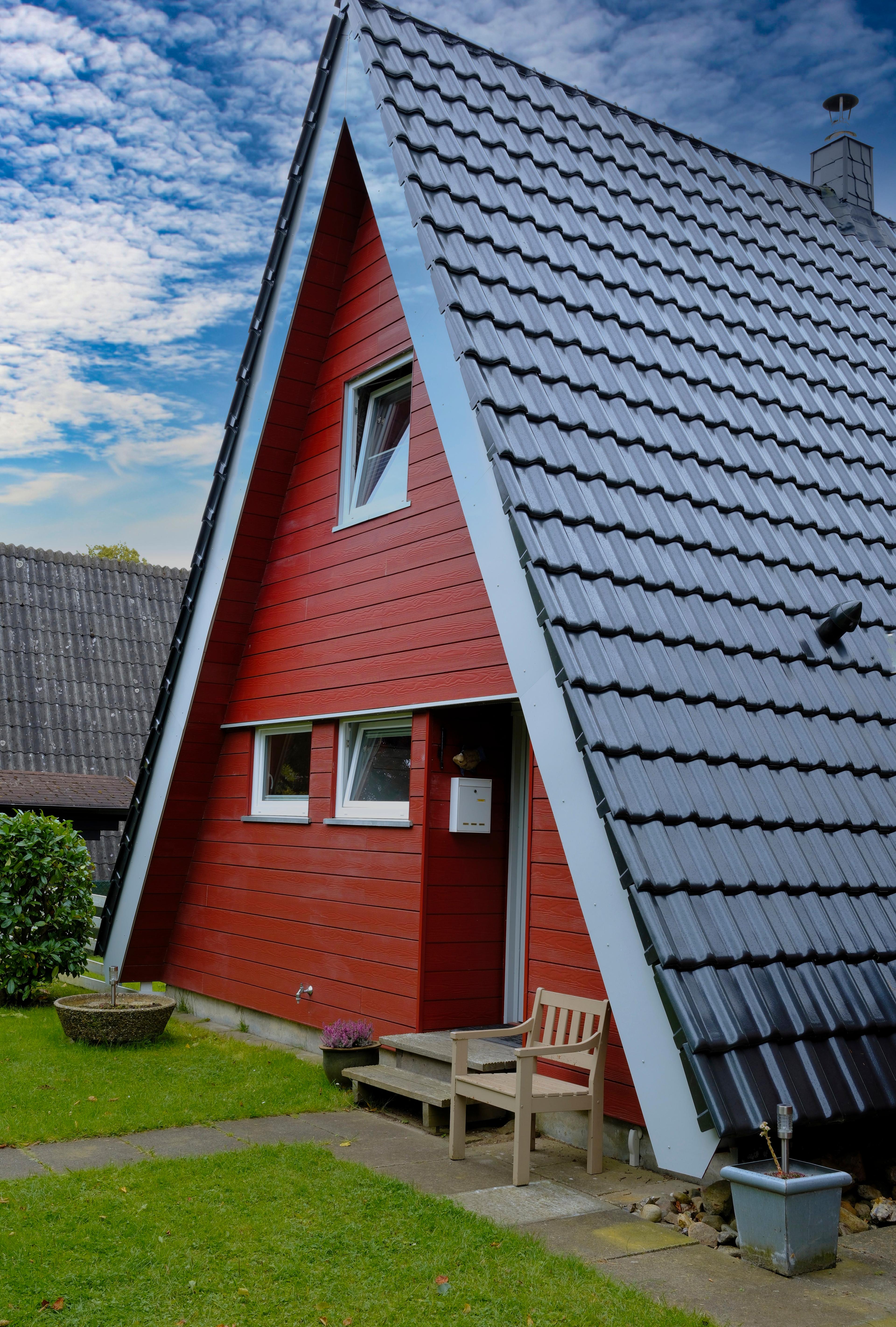 Ein rotes A-Frame-Haus mit grauem Dach und kleinem Garten